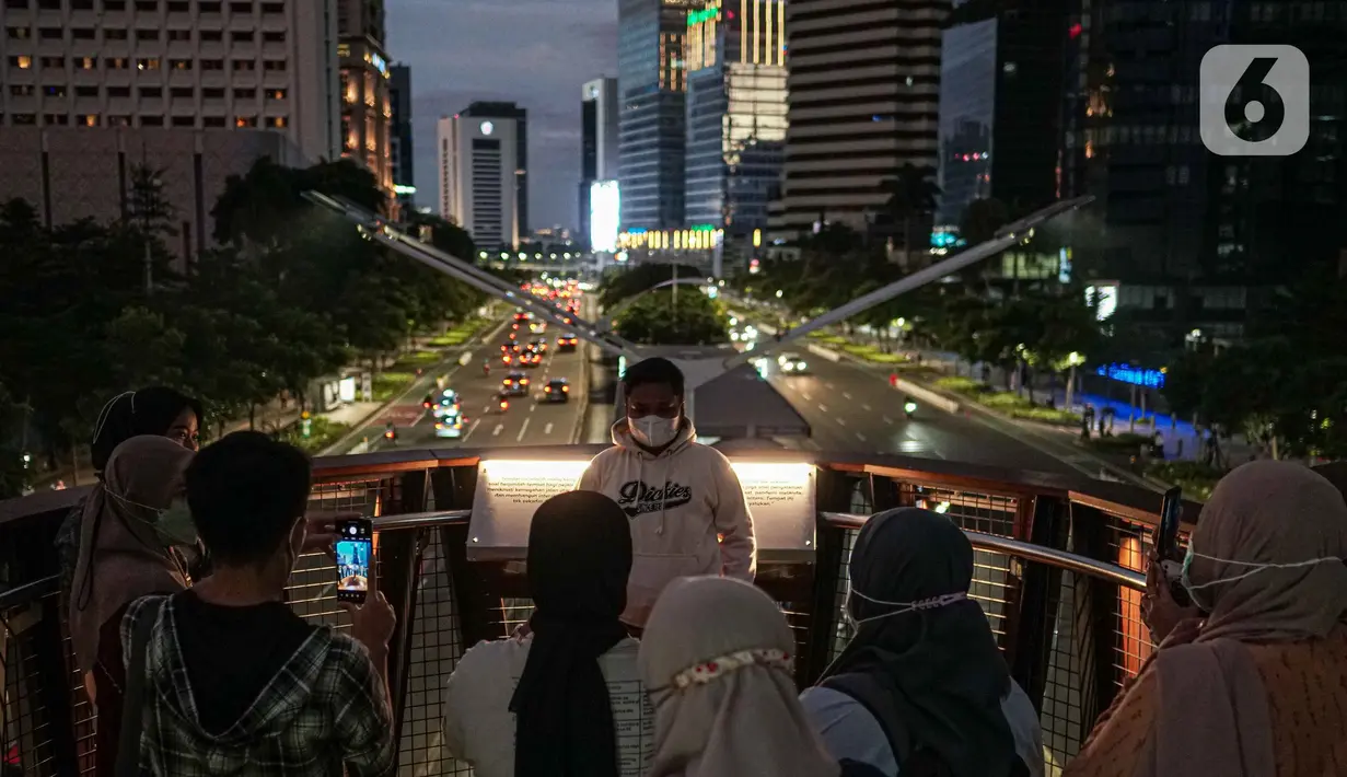 Warga berfoto di balkon Jembatan Penyeberangan Orang dan Sepeda (JPOS Phinisi) di kawasan Karet, Jakarta, Minggu (20/3/2022). JPOS Phinisi kini menjadi objek baru bagi warga Jakarta. (Liputan6.com/Faizal Fanani)