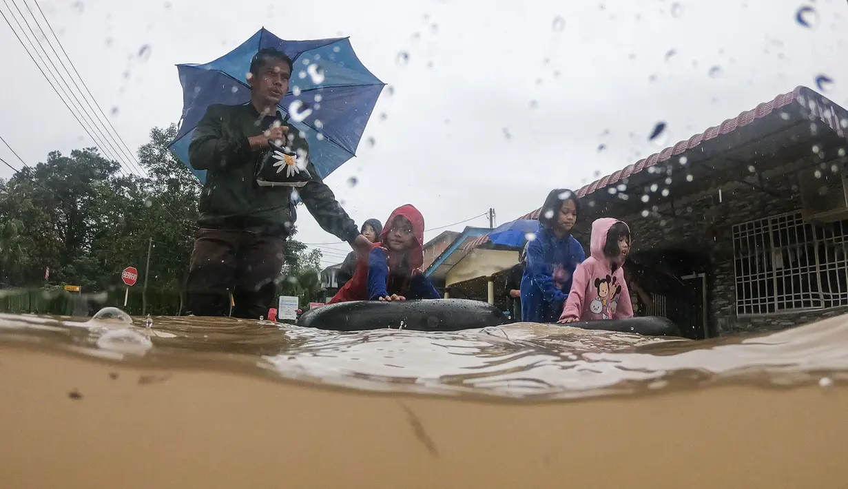 Sebuah keluarga mengarungi banjir setelah mengevakuasi rumah mereka di daerah banjir di Yong Peng, negara bagian Johor Malaysia, Sabtu (4/3/2023). Departemen meteorologi memperingatkan lebih banyak hujan dalam beberapa hari mendatang, terutama sebagian besar di negara bagian selatan. (Photo by Mohd RASFAN / AFP)