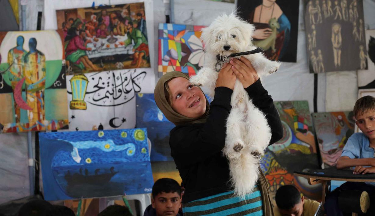 Sementara, penggunaan studio seni diharapkan menjadi ruang ekspresi untuk mengurangi rasa takut dan kecemasan anak-anak pengungsi Palestina. Anak-anak pengungsi Palestina mengikuti sesi konseling psikologis di sebuah studio seni yang menggunakan hewan peliharaan dan burung di daerah Al-Zawaida, Jalur Gaza Tengah, pada Selasa 21 April 2026. (Eyad Baba/AFP)