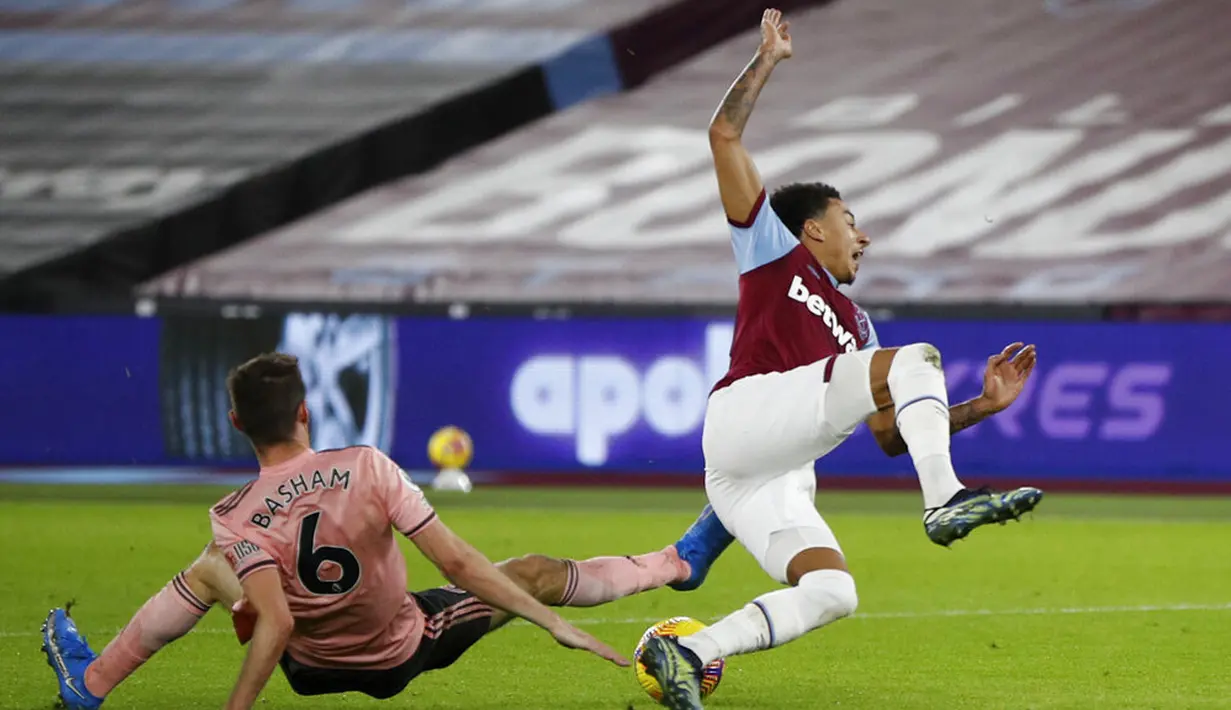 Pemain West Ham United Jesse Lindgard (kanan) dilanggar oleh pemain Sheffield United Chris Basham pada pertandingan Liga Inggris di London Stadium, London, Inggris, Senin (15/2/2021). West Ham United menang 3-0. (John Sibley/Pool via AP)