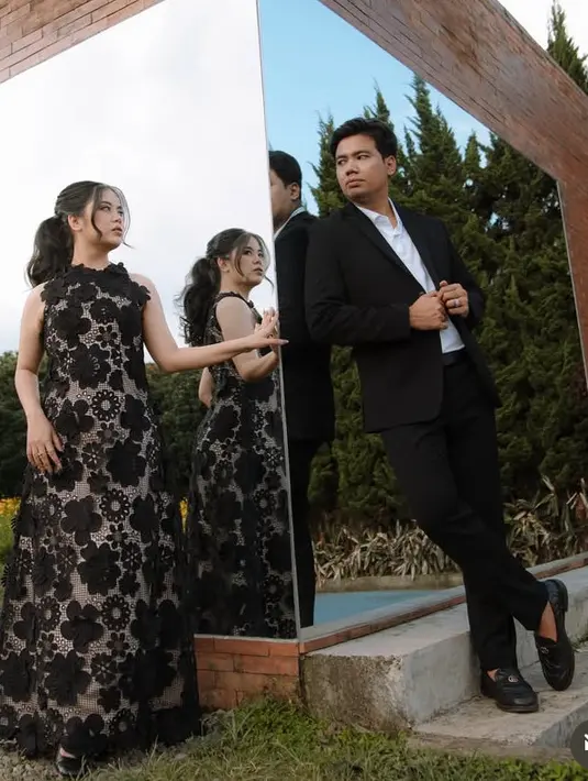 Sedangkan Indah tampak feminim mengenakan dress panjang sleeveless warna hitam dengan aksen bunga 3D. Rambutnya diikat ke belakang model ponytail. [@fransfaisal_]