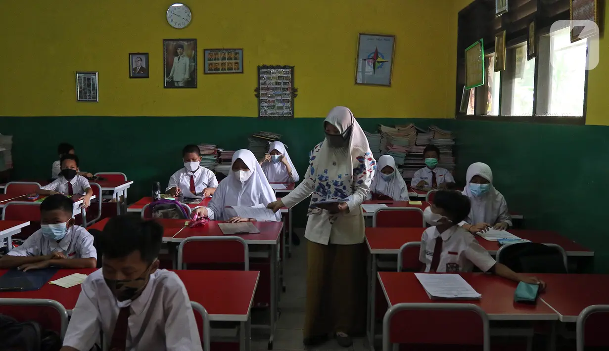 Guru membagikan lembar soal kepada sejumlah murid SDN Kota Baru saat ujian penilaian akhir sekolah di SDN Kota Baru 3 Bekasi, Jawa Barat, Senin (8/6/2021). Ujian yang dilaksanakan secara tatap muka tersebut diikuti kelas 4 dan 5. (Liputan6.com/Herman Zakharia)