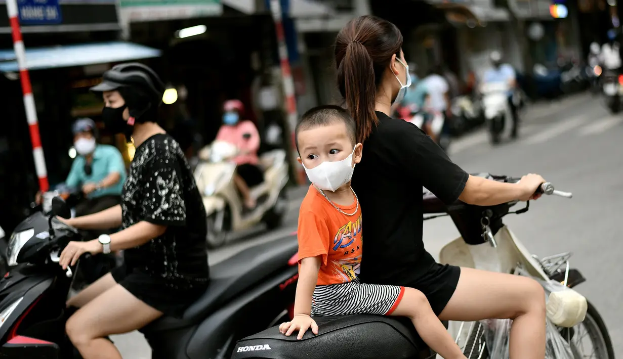 Anak laki-laki melihat ke belakang saat mengendarai skuter dengan seorang perempuan di Hanoi, ibu kota Vietnam pada 11 Agustus 2020. Setelah mencatat nol kasus COVID-19 selama lebih dari tiga bulan, Vietnam melaporkan sejumlah infeksi baru di dalam negeri sejak akhir Juli. (MANAN VATSYAYANA/AFP)