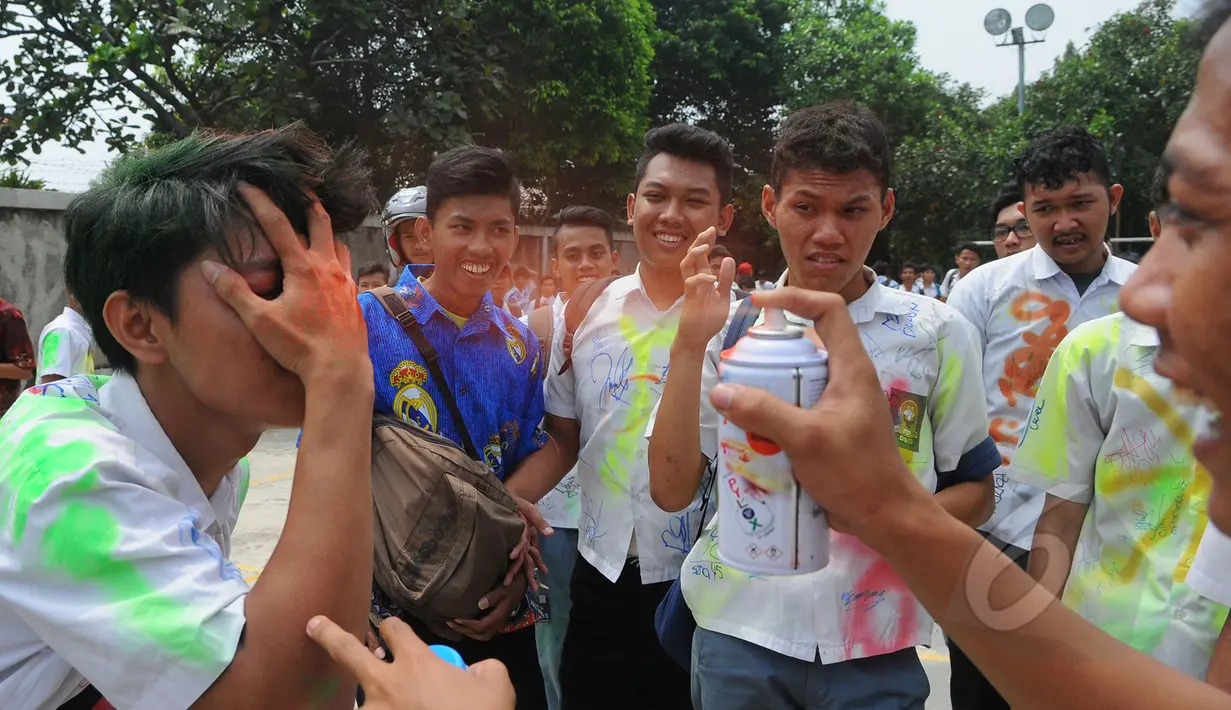 Pelajar SMK Kemala Bhayangkari 1 Jakarta, mencoret rambut temannya dengan cat semprot usai mengikuti Ujian Nasional (UN), Kamis (16/4/2015). Aksi tersebut dilakukan sebagai bentuk kegembiraan usai mengikuti UN. (Liputan6.com/Herman Zakharia)