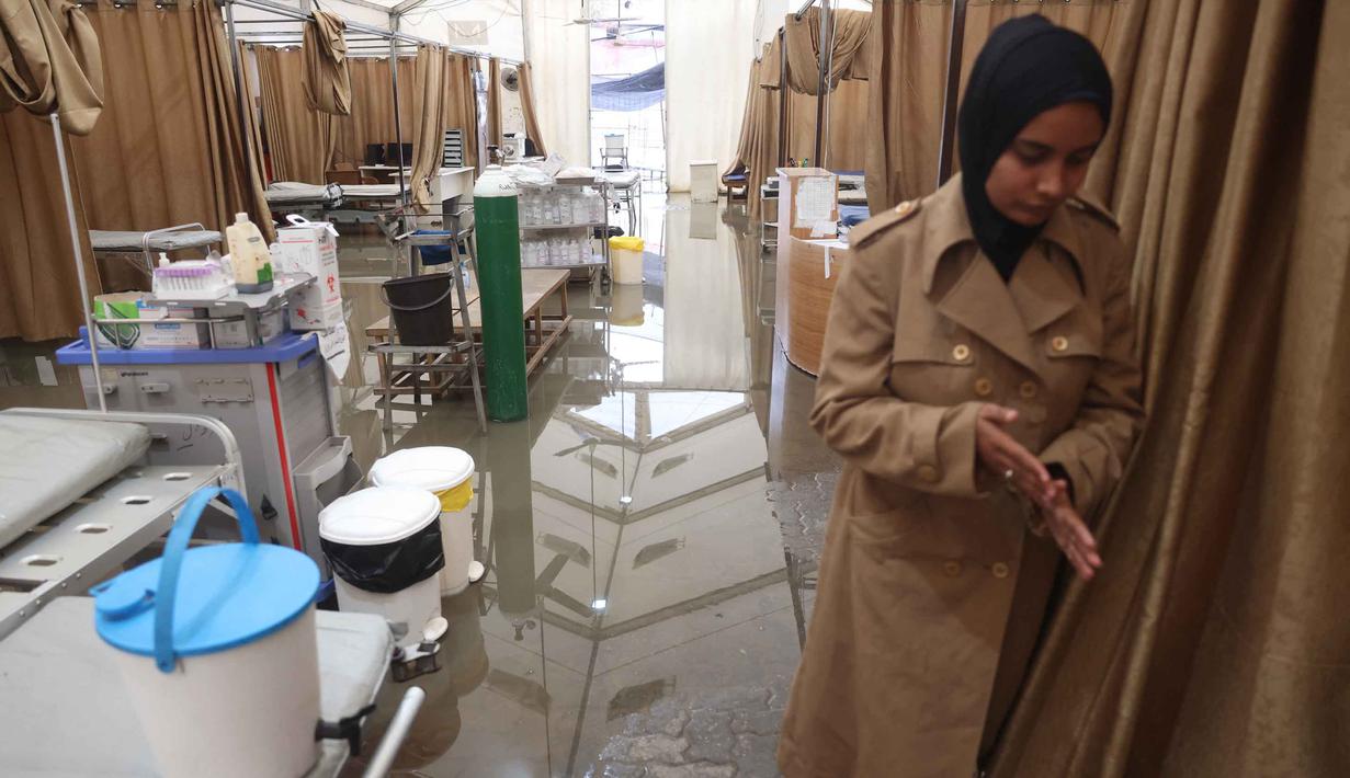 Tenda darurat tersebut diketahui berfungsi sebagai area layanan penerimaan pasien rawat jalan dan departemen gawat darurat. Tampak dalam foto, genangan air menutupi lantai tenda darurat milik Rumah Sakit Nasser, yang berfungsi sebagai tempat penerimaan pasien rawat jalan dan departemen gawat darurat, setelah hujan lebat di Khan Yunis di Jalur Gaza selatan pada 26 Maret 2026. (Bashar Taleb/AFP)