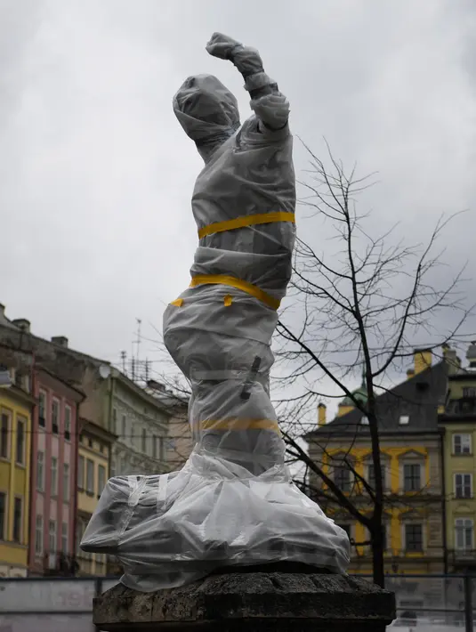 Patung yang dibungkus dengan plastik pelindung di dekat dewan kota di Lviv barat Ukraina, pada 5 Maret 2022. Warga kota Lviv membungkus semua patung yang ada di kota tersebut untuk melindungi warisan sejarahnya dari kerusakan akibat serangan di tengah konflik Rusia-Ukraina. (Daniel LEAL/AFP)