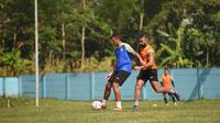 Yann Motta (rompi biru) dibayangi Dalberto Luan dalam sesi latihan Arema FC di lapangan ARG, Kabupaten Malang, Rabu (02/07/2025). (Iwan Setiawan/Bola.com)