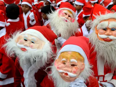 Anak-anak sekolah India mengenakan kostum Santa Claus berpose saat mereka mengambil bagian dalam acara Natal di sebuah sekolah di Chennai, (5/12). Natal adalah hari raya umat Kristen yang diperingati setiap tanggal 25 Desember. (AFP Photo/Arun Sankar)