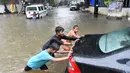 Sejumlah anak mendorong sebuah mobil yang mogok akibat melintasi banjir saat hujan deras di Mumbai, India (9/7). Mumbai dan daerah pinggiran lainnya telah mengalami hujan lebat semalaman yang mengakibatkan banjir. (AFP Photo/Indranil Mukherjee)