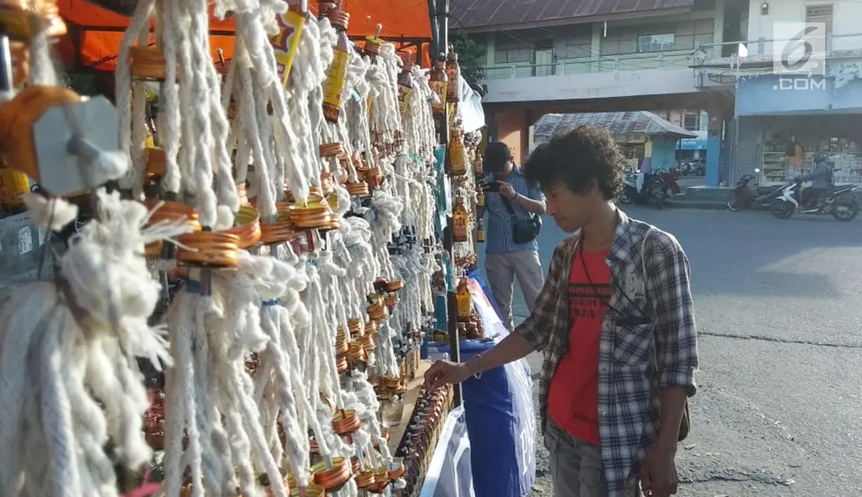 Pedagang merapikan pelita dagangannya yang dijual di Jalan Sam Ratulangi, Kota Gorontalo, Rabu (22/5/2019). Pelita yang terbuat dari botol bekas tersebut dijual dengan harga Rp 5 ribu hingga Rp 12 ribu per buah. (Liputan6.com/Arfandi Ibrahim)