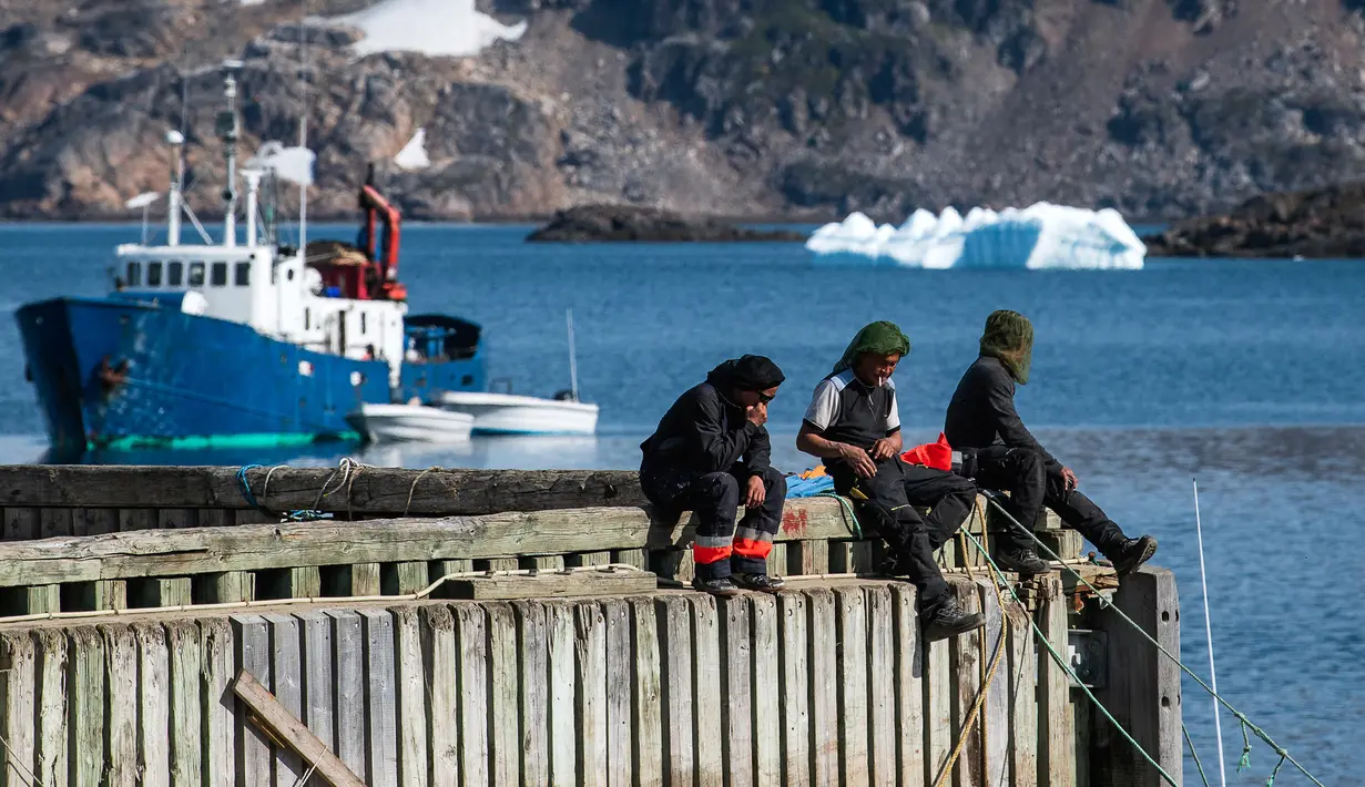 Sejumlah warga duduk di dermaga Desa Kulusuk, Kota Sermersooq, Greenland, Denmark, 16 Agustus 2019. Belakangan, angka pengangguran di Desa Kulusuk cukup tinggi dan populasi penduduknya turun. (Jonathan NACKSTRAND/AFP)
