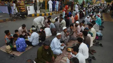 Muslim Pakistan berdoa sebelum berbuka puasa bersama di sepanjang jalan di Karachi pada 7 Mei 2019. Ketika bulan suci Ramadan mulai di Pakistan, banyak masyarakat muslim memanfaatkan buka puasa gratis yang disponsori oleh badan-badan amal dan orang-orang kaya. (RIZWAN TABASSUM / AFP)