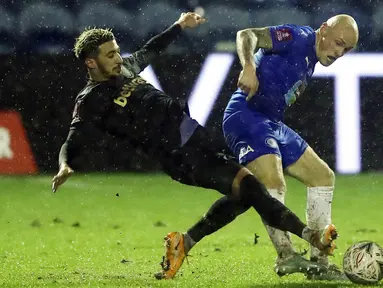 Pemain Stockport County, Sam Minihan, berebut bola dengan pemain West Ham United, Said Banrahma, pada laga Piala FA di Stadion Edgeley Park, Senin (11/1/2021). West Ham United menang dengan skor tipis 1-0. (Martin Rickett/Pool via AP)