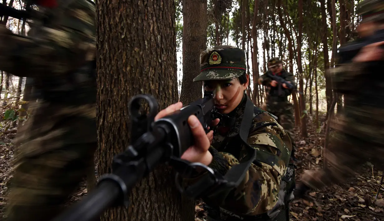 Tentara wanita China melakukan simualisi perang di tengah hutan saat melakukan latihan militer jelang Hari Perempuan Internasional di Hefei, China (6/4). (AFP)