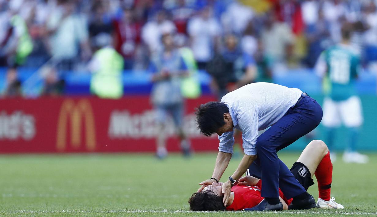 Pelatih Korea Selatan, Shin Tae-yong, membangunkan anak asuhnya, Lee Jae-sung, usai melawan Jerman pada laga Piala Dunia di Kazan Arena, Rusia (27/6/2018). Jerman takluk 0-2 dari Korea Selatan. (AFP/Benjamin Cremel)