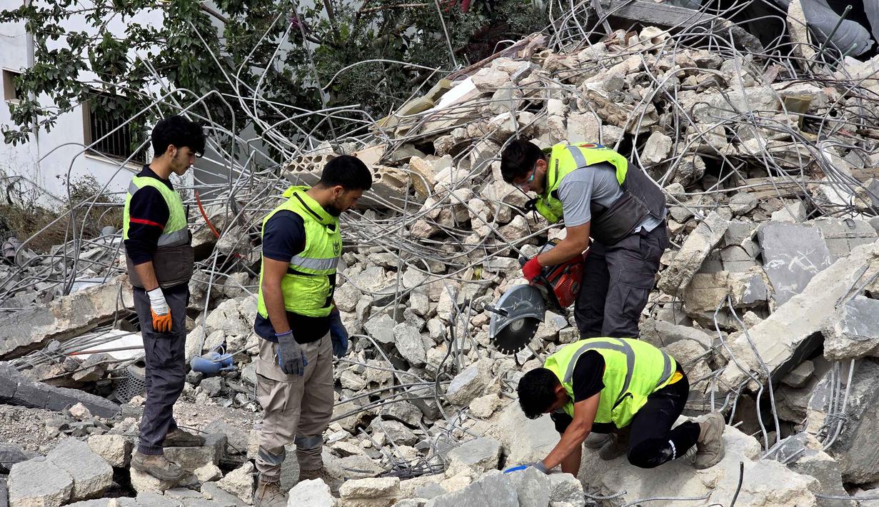 Para pekerja pertahanan sipil Lebanon menyisir reruntuhan, sehari setelah serangan Israel di desa Deir Qanun al-Nahr, Lebanon Selatan, pada Rabu 20 Mei 2026. (KAWNAT HAJU/AFP)