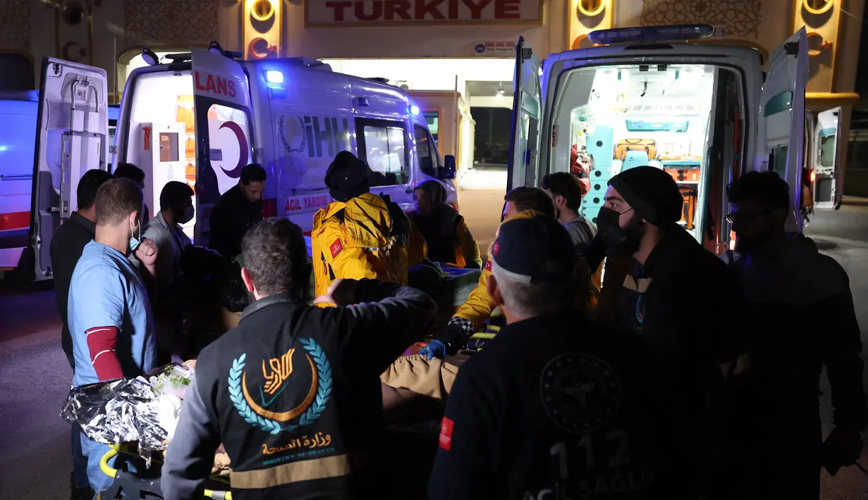 Petugas medis mengangkut Sham Sheikh Mohammed ke ambulans di perbatasan Bab al-Hawa pada 23 Februari 2023, sebelum memasuki Turki untuk perawatan. Sham, seorang gadis Suriah berusia sembilan tahun yang nasibnya menangkap tragedi, harapan dan patah hati gempa bulan ini setelah menghabiskan 40 jam di bawah reruntuhan dibawa ke Turki untuk dirawat. (AFP/OMAR HAJ KADOUR)