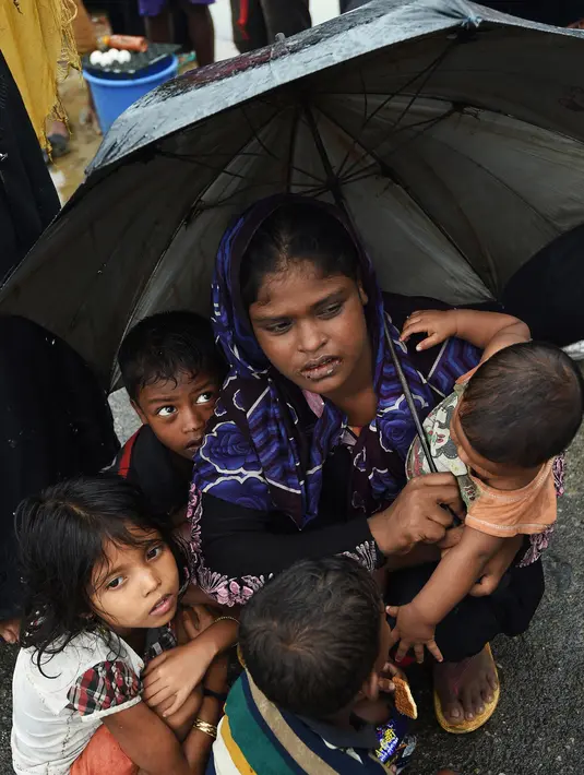 Pengungsi Rohingya bersama anaknya menunggu bantuan di DWIP Sha Porir di Teknef (20/9). Tentara Bangladesh diperintahkan untuk membantu ratusan ribu orang Rohingya yang telah melarikan diri dari kekerasan di Myanmar. (AFP Photo/Dominique)