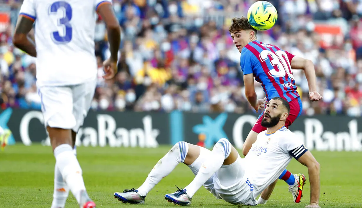 Pemain Barcelona Gavi Paez (​​belakang) berebut bola dengan pemain Real Madrid Karim Benzema pada pertandingan La Liga Spanyol di Stadion Camp Nou, Barcelona, Spanyol, Minggu (24/10/2021). Real Madrid menang 2-1. (AP Photo/Joan Monfort)