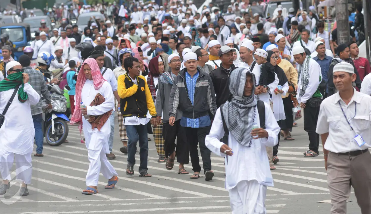 Puluhan orang berjalan kaki menuju Monas dari arah Tanah Abang, Jakarta, Jumat (2/12). Mereka terlihat berbondong-bondong berjalan untuk mengikuti demo 2 Desember di Lapangan Monas. (Liputan6.com/Helmi Afandi)