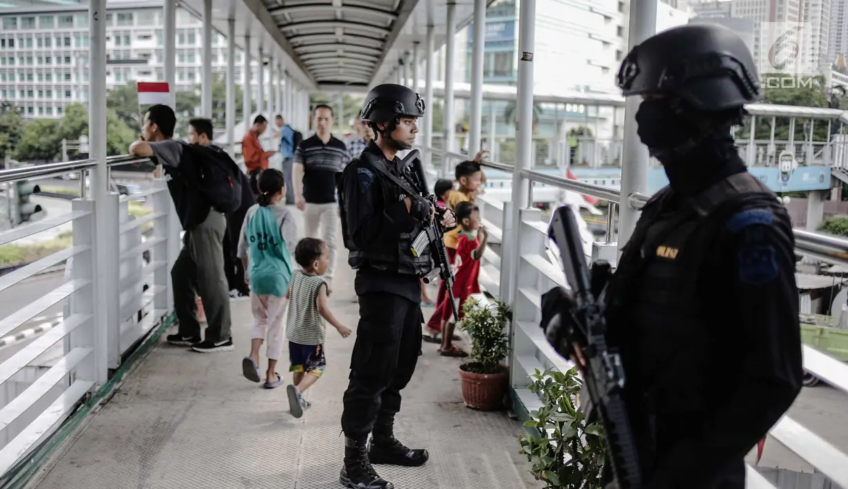 Dua anggota Brimob bersenjata lengkap berjaga di JPO kawasan Bunderan HI, Jakarta, Jumat (11/5). Penjagaan tersebut dilakukan untuk antisipasi kegiatan Aksi 115 Pembebasan Baitul Maqdis yang berpusat di Monas. (Liputan6.com/Faizal Fanani)