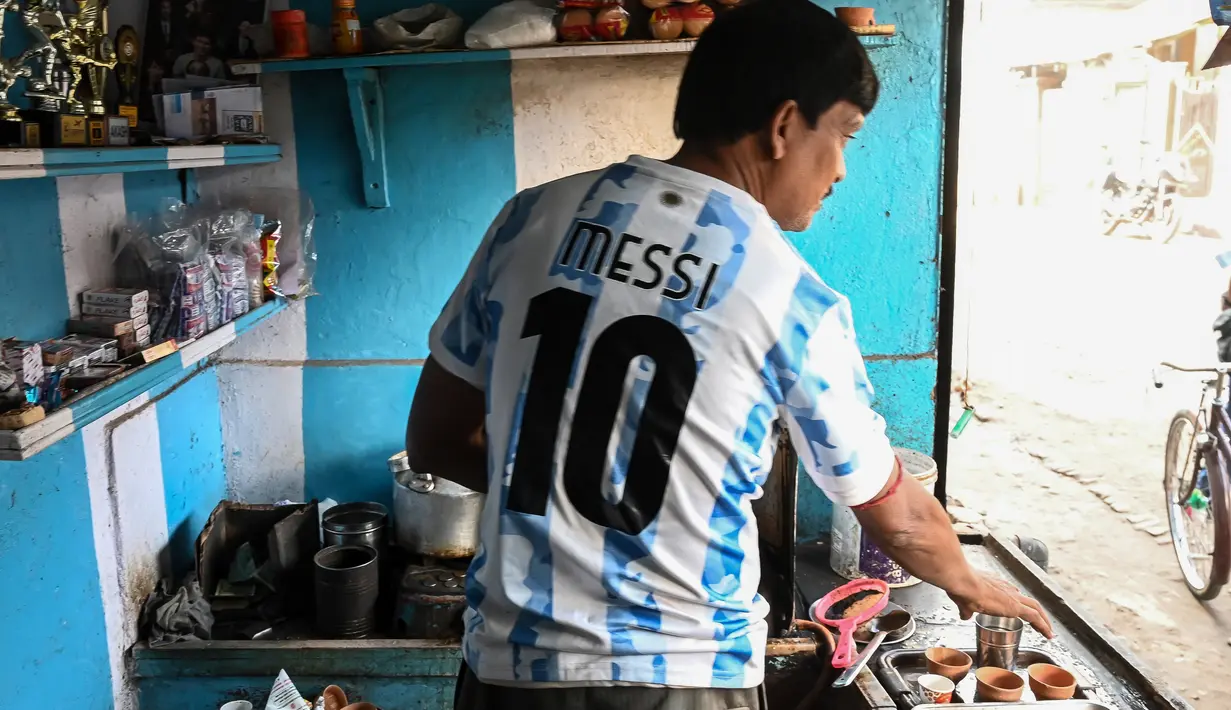 Pemilik warung teh, Shib Shankar Patra sebagai fans timnas Argentina mengenakan jersey saat bekerja di dalam warung tehnya yang dicat dengan warna tim di Ichhapur sekitar 35 km sebelah utara Kolkata pada 12 Desember 2022. Argentina berhasil lolos ke babak semifinal Piala Dunia 2022 Qatar yang akan melawan Kroasia. (AFP/Dibyangshu Sarkar)