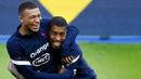 Penyerang Prancis, Kylian Mbappe, bercanda dengan Presnel Kimpembe, saat sesi latihan jelang laga UEFA Nations League di Paris, Senin (7/9/2020). Pemain muda PSG itu akan absen melawan Kroasia karena dinyatakan positif terjangkit COVID-19. (AFP/Franck Fife)