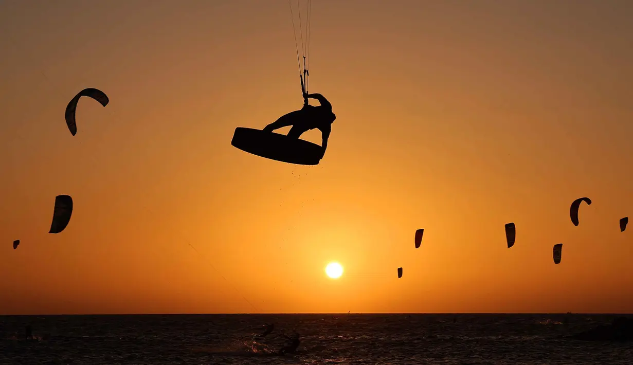 Warga Israel berolahraga Selancar Layang (kitesurfing) saat matahari terbenam di lepas pantai Tel Aviv, pada 21 Oktober 2025. (JACK GUEZ/AFP)
