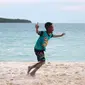 Seorang bocah melakukan selebrasi usai mencetak gol saat bermain bola dekat pantai di Desa Matwaer, Kei Kecil, Maluku (25/12/2017). Bermain bola di pasir menjadi daya tarik tersendiri bagi anak-anak dan pemuda desa. (Bola.com/Nick Hanoatubun)