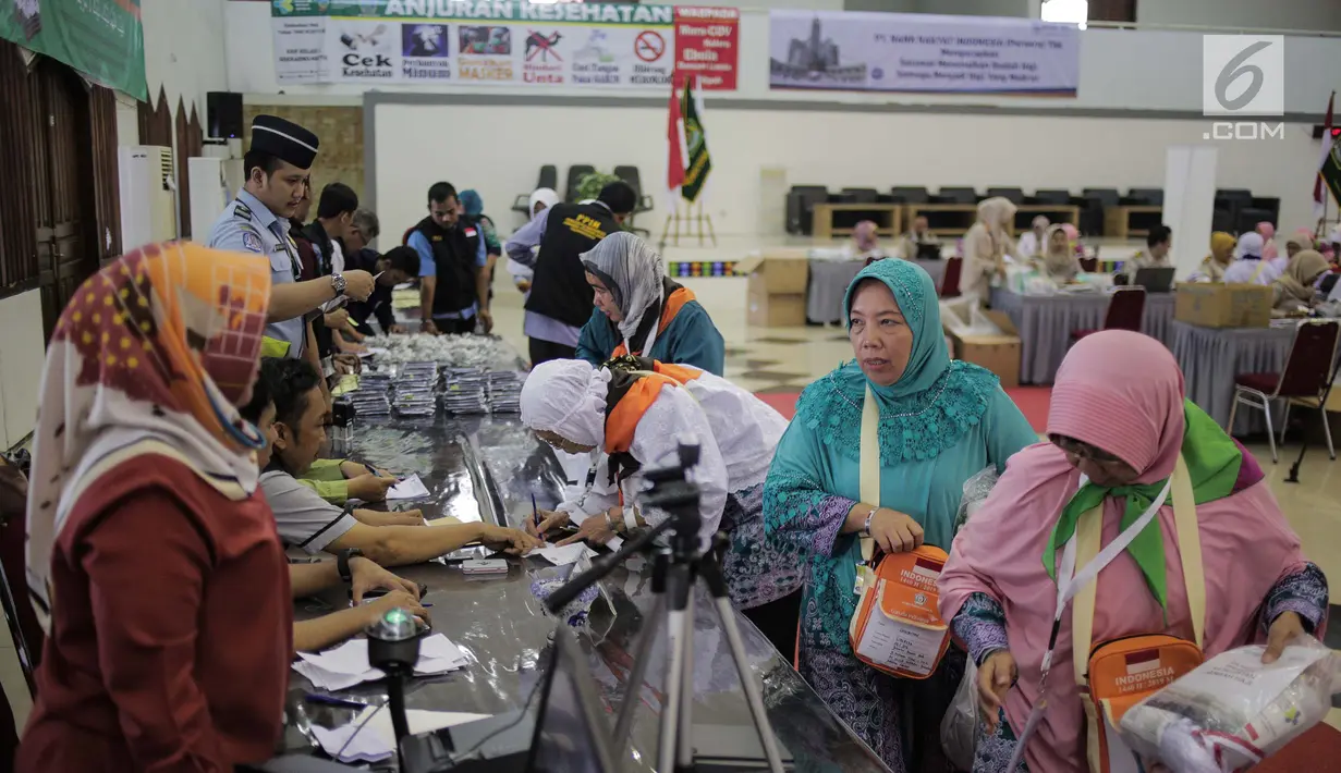 Panitia Penyelenggara Ibadah Haji (PPIH) memberikan perlengkapan untuk calon jemaah haji kloter pertama di Asrama Haji, Jakarta, Sabtu (6/7/2019). Pengecekan kelengkapan administrasi berupa cek kesehatan, foto biometrik dan sidik jari untuk keperluan imigrasi di embarkasi. (Liputan6.com/Faizal Fanan