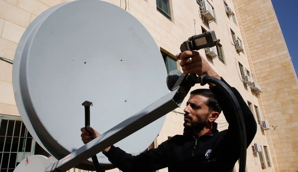 Pegawai Trans Media memeriksa sebuah satelit di kantornya setelah penutupan oleh pasukan Israel di kota Hebron, Tepi Barat, Rabu (18/10). Dalam penggerebekan, delapan perusahaan media diperintahkan untuk berhenti beroperasi. (HAZEM BADER/AFP)