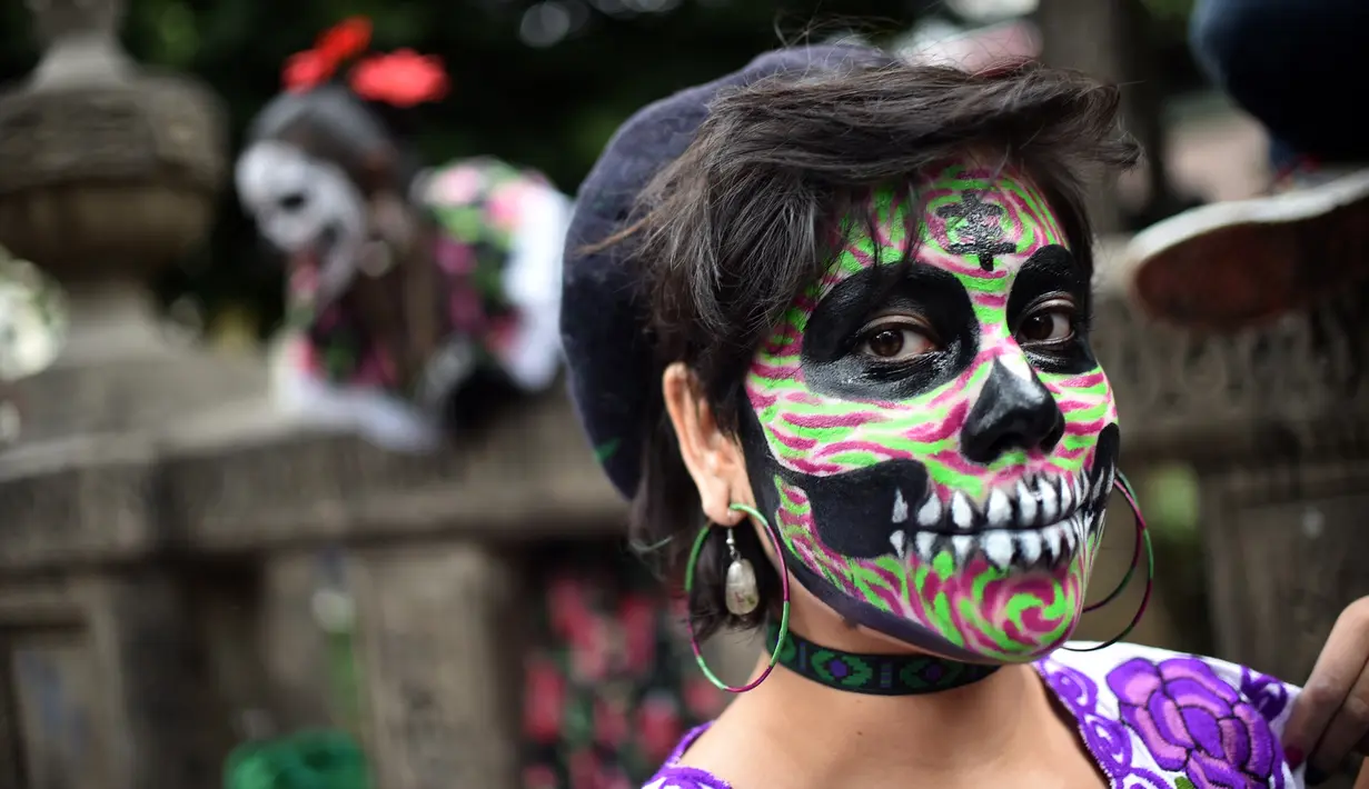 Seorang wanita berpakaian seperti "Catrina" ambil bagian dalam parade catrinas atau Hari Orang Mati di Reforma Avenue, Mexico City, 21 Oktober 2018. La Catrina diciptakan oleh artis Meksiko Jose Guadalupe Posada. (RODRIGO ARANGUA/AFP)