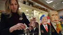 Penjaga toko manampilkan Matryoshka yang berkarakter Putin dan Trumph di Moskow, Rusia (16/1). Matryoshka adalah boneka kayu bertumpuk yang berasal dari Rusia. (AFP/Alexander Nemenov)