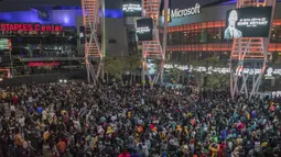 Sejumlah warga berkumpul untuk mengenang wafatnya Kobe Bryant di Staples Center, Los Angeles, Minggu (26/1). Akibat kecelakaan helikopter, legenda NBA itu wafat bersama sang putri. (AFP/Apu Gomes)