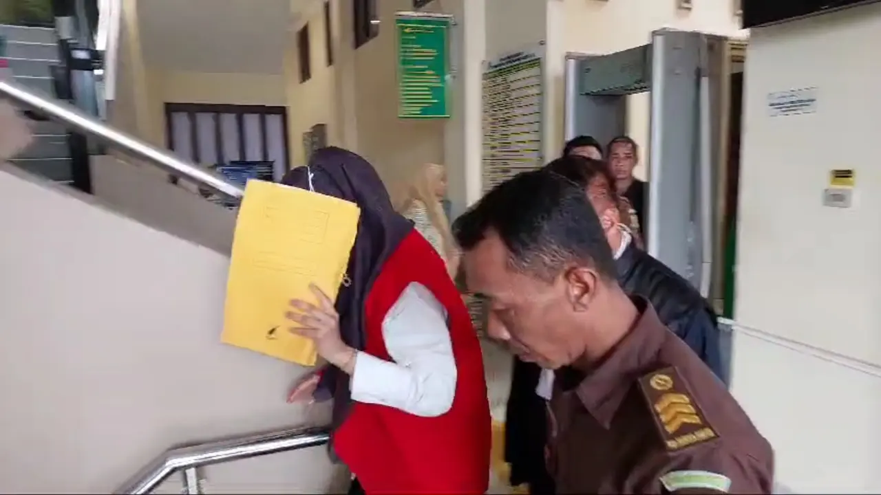 Adelia Putri Salma menutupi wajahnya menggunakan map berwarna kuning demi menghindari sorotan kamera wartawan. Foto : (Liputan6.com/Ardi)