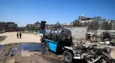 Seorang anak laki-laki mengambil air ke dalam jeriken dari kendaraan mobile tangki air yang hancur akibat pengeboman Israel di kamp Nuseirat untuk pengungsi Palestina di Jalur Gaza tengah pada 14 Juli 2025. (Eyad BABA/AFP)
