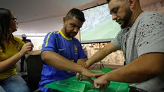 Suporter Brasil yang buta dan tuli, Carlos Junior merasakan berlangsungnya pertandingan 16 besar Piala Dunia 2018 antara Brasil melawan Meksiko dibantu penerjemah dengan miniatur lapangan sepak bola di Sao Paulo, Brasil, (2/7). (AP Photo / Nelson Antoine)