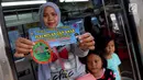 Seorang wanita menunujukkan stiker informasi pengaduan kekerasan di sekitar Stasiun Tanah Abang, Jakarta, Kamis (21/12). Stiker ini bertuliskan informasi tentang pengaduan ketika terjadi kekerasan pada wanita dan anak. (Liputan6.com/JohanTallo)