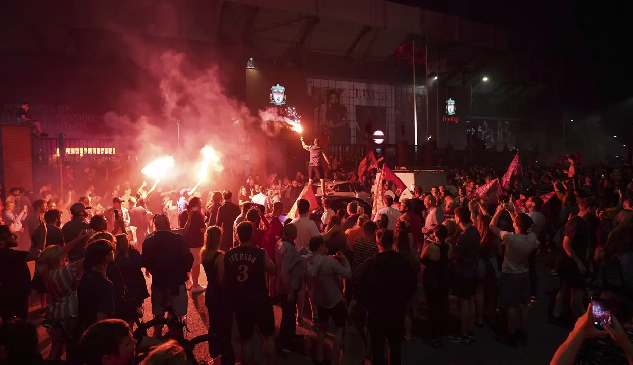Suporter Liverpool merayakan gelar juara Premier League di depan Stadion Anfield, Kamis (25/6/2020). Titel juara Liga Inggris 2019-20 ini merupakan gelar pertama Liverpool setelah puasa selama 30 tahun. (AP/Jon Super)