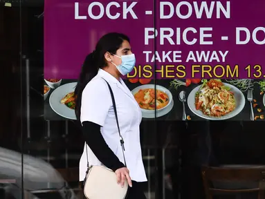 Seorang wanita yang mengenakan masker berjalan melewati sebuah restoran di Melbourne, Negara Bagian Victoria, Australia, 31 Agustus 2020. Kasus baru COVID-19 di Victoria turun setelah sebulan memberlakukan karantina wilayah (lockdown) Tahap 4 di ibu kotanya, Melbourne. (Xinhua/Bai Xue)