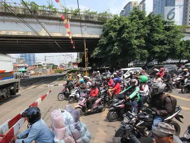 Pengendara menanti di pintu perlintasan kereta sebidang di Jalan KH Mas Mansyur, Jakarta, Senin (30/10). Perlintasan sebidang ini rencananya segera ditutup karena dianggap menjadi salah satu titik kemacetan di Jakarta Pusat. (Liputan6.com/Angga Yuniar)