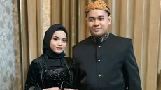 Putri Isnari membagikan potret terbarunya bareng suami ketika menghadiri prosesi siraman sekaligus mappaci calon suami Nia LIDA. Dalam momen bahagia tersebut, Putri tampil kompak dengan Abdul Azis mengenakan busana adat Jawa bernuansa hitam. (Liputan6.com/IG/@putriisnari3)