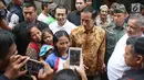 Warga berfoto bersama Presiden Jokowi saat menyaksikan pembagian paket Ramadan di wilayah Penjaringan, Jakarta, Selasa (13/6). Sebanyak 200.000 paket dibagikan gratis untuk meringankan beban masyarakat menjelang Idul Fitri. (Liputan6.com/Angga Yuniar)