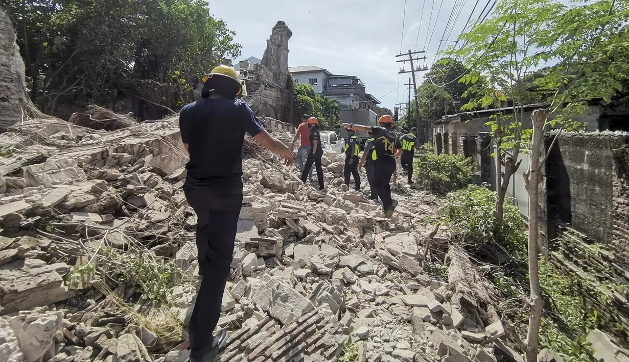Penyelamat berjalan melewati puing-puing bangunan yang runtuh setelah gempa kuat melanda Vigan, Provinsi Ilocos Sur, Filipina, 27 Juli 2022. Sebanyak empat orang dilaporkan tewas dan puluhan lainnya terluka dalam akibat gempa. (Bureau of Fire Protection via AP)