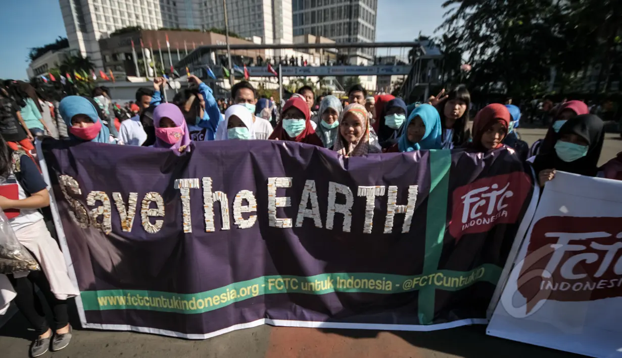 Aktivis Gerakan Muda FCTC membentangkan spanduk 'Save The Earth' saat melakukan Aksi Selamatkan Bumi dari Limbah Puntung Rokok di kawasan Bundaran HI, Jakarta, Minggu (26/4/2015). (Liputan6.com/Faial Fanani)