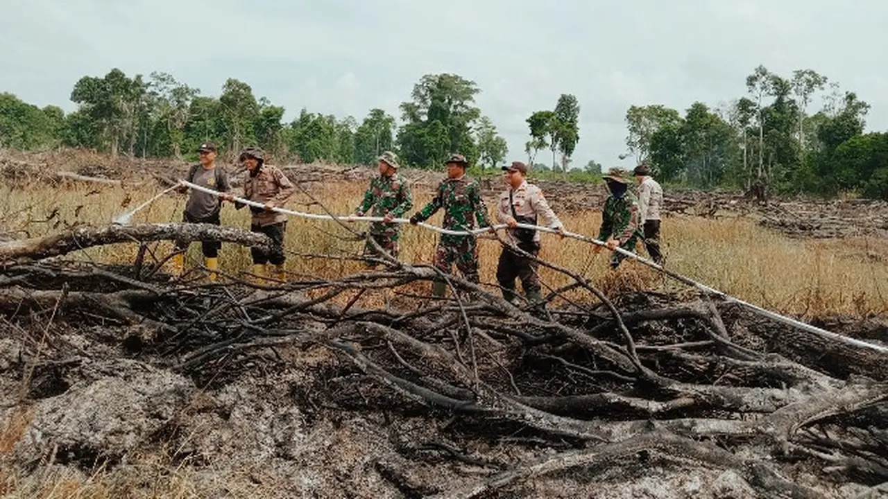 Polisi dan TNI mendinginkan lokasi kebakaran lahan di Rokan Hilir.