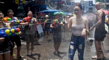 Warga menyemprotkan air ke seorang wanita saat merayakan Festival Songkran atau Tahun Baru Thailand di Bangkok, Thailand, 13 April 2019. Warga Thailand mengisi Festival Songkran dengan bersenang-senang, salah satunya perang air. (Lillian SUWANRUMPHA/AFP)