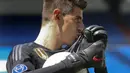 Kiper baru Real Madrid, Thibaut Courtois, mencium lambang klub saat diperkenalkan di Stadion Santiago Bernabeu, Madrid, Kamis (9/8/2018). Pemain berusia 26 tahun pindah setelah empat musim terakhir jadi kiper utama Chelsea. (AP/Andrea Comas)
