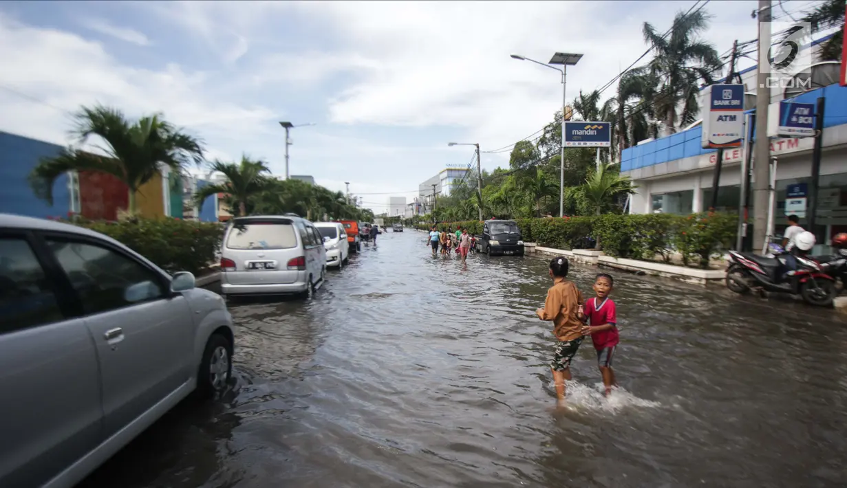 Sejumlah anak-anak bermain di genangan banjir rob di kawasan Muara Baru, Jakarta, Rabu (6/11). (Liputan6.com/Faizal Fanani)