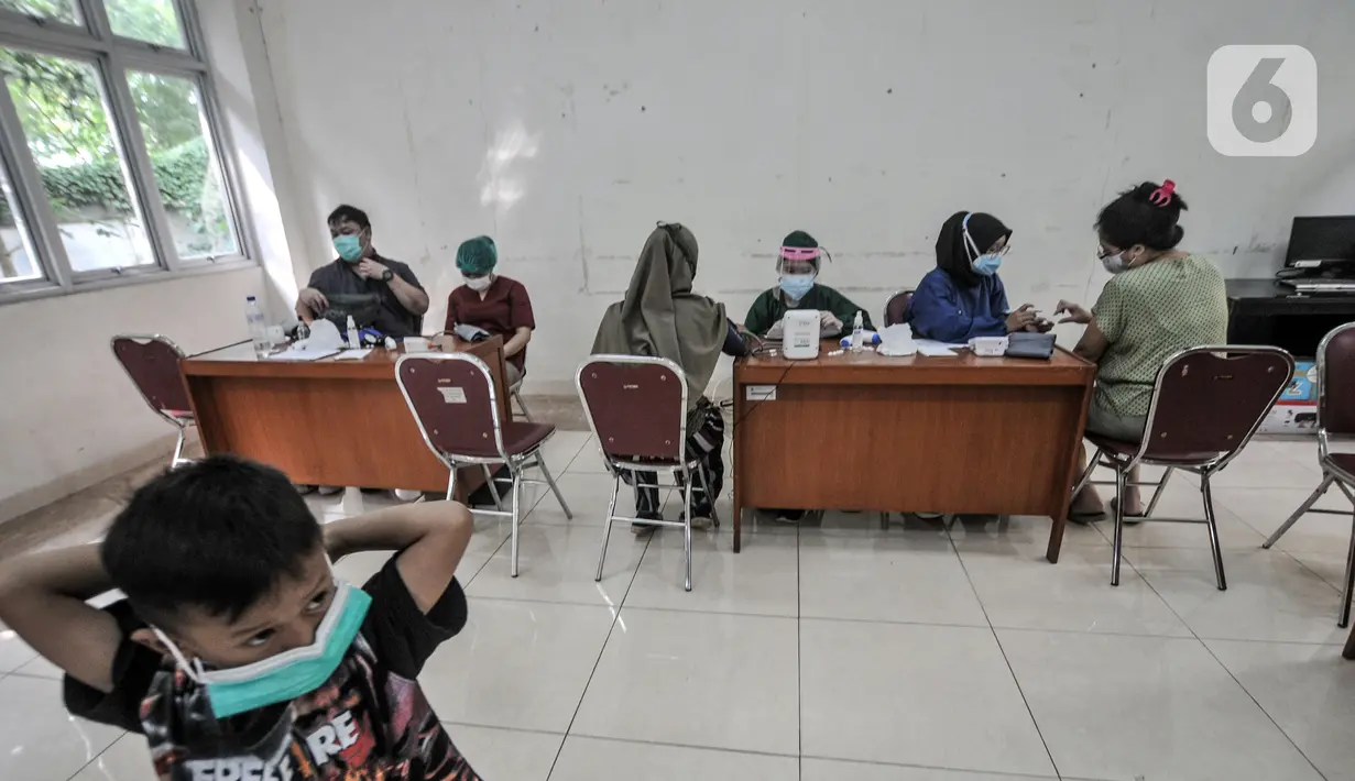 Suasana pelaksanaan vaksinasi COVID-19 di Kantor Kelurahan Ancol, Jakarta, Kamis (17/6/2021). Pembagikan sembako gratis kepada peserta vaksinasi COVID-19 dilakukan LMK Kelurahan Ancol sebagai upaya mendorong minat warga. (merdeka.com/Iqbal S. Nugroho)